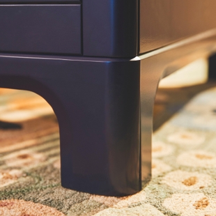 Close-up detail of a curved wooden leg of the crib.